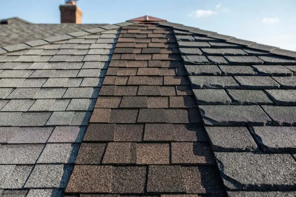 Roof where lighter gray asphalt shingles meet a strip of darker brown shingles, showing two shingle styles side by side